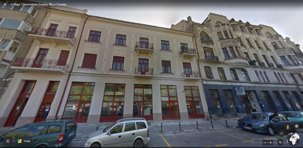 a large building with cars parked in front of it at Apartment First December in Oradea