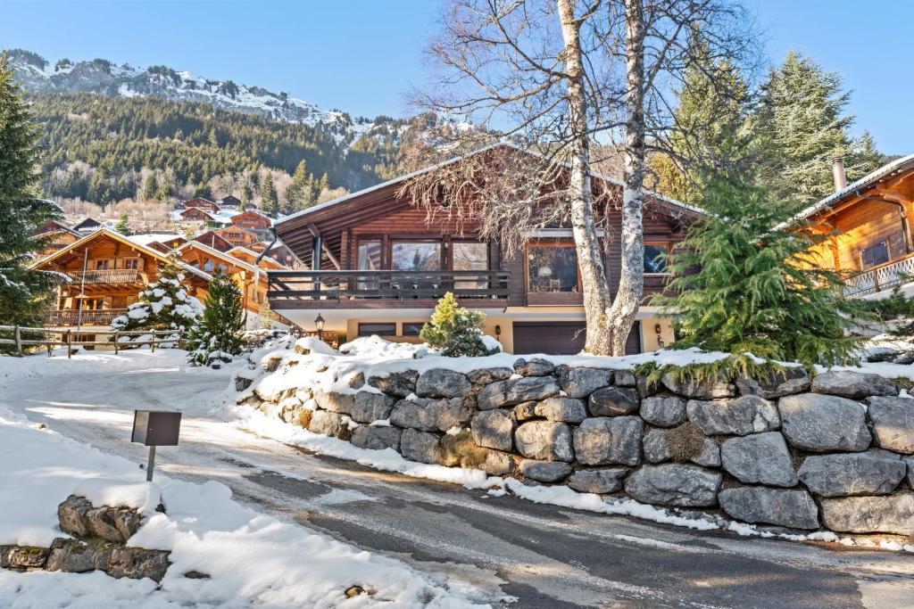 a log home in the snow with a stone wall at Chalet Nirvana by Mrs Miggins in Champéry