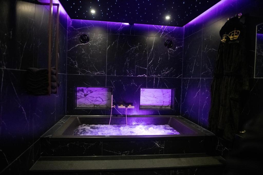 - une baignoire avec éclairage violet dans la chambre dans l'établissement Royal Suite, à s-Gravenzande