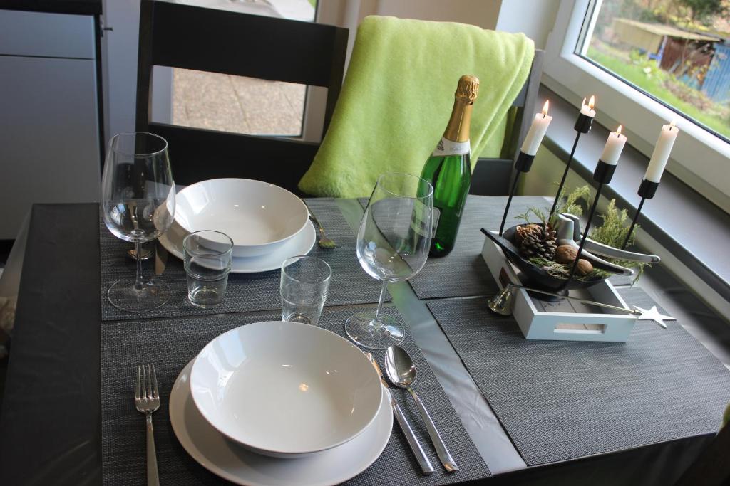 einen Tisch mit Tellern und Gläsern sowie eine Flasche Wein in der Unterkunft Fewo Traumblick in Kreuzwertheim