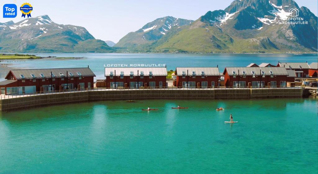a group of buildings in the water with mountains at Lofoten rorbuutleie - Lilleeidet in Gravdal