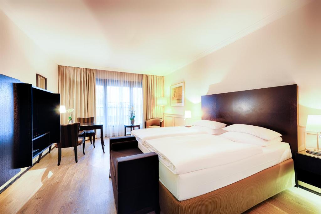 オイスキルヒェンにあるWelcome Parkhotel Euskirchenの大きなベッドとテーブルが備わるホテルルームです。