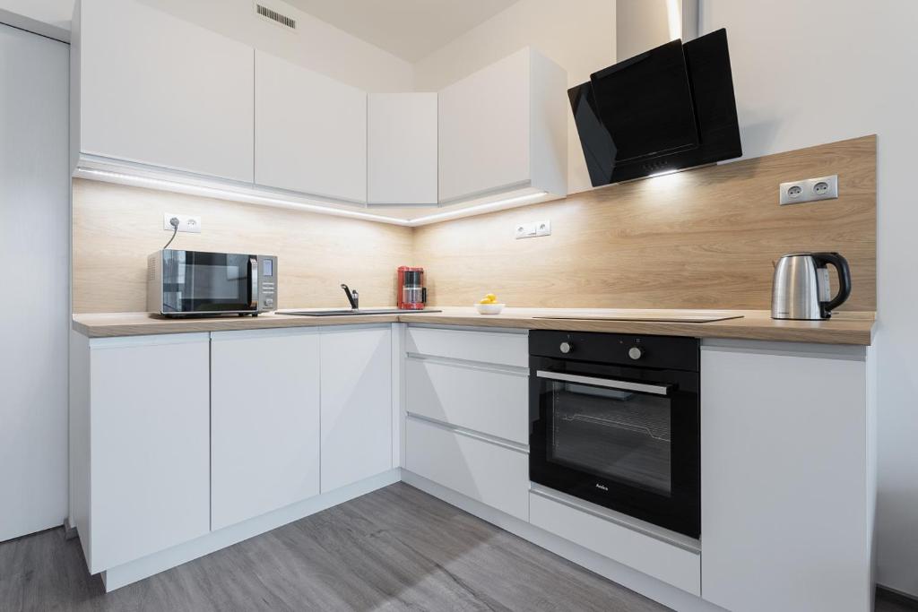 a kitchen with white cabinets and a black oven at Yellow apartment with PARKING in Prague