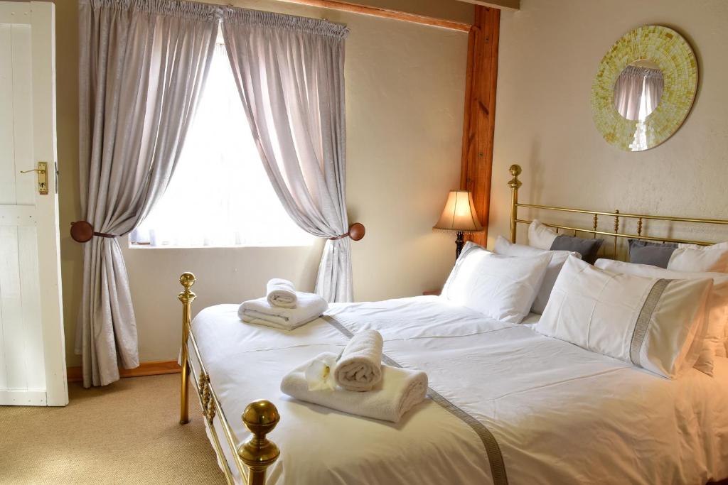 a bedroom with a large white bed with towels on it at Villa Moria Peace Cottage in Dullstroom