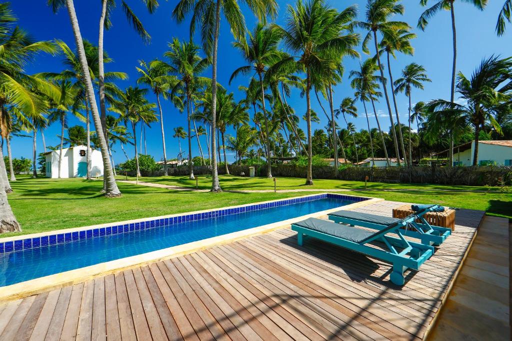 佩德拉斯港的住宿－Pousada Patacho，一个带蓝色长凳和棕榈树的游泳池