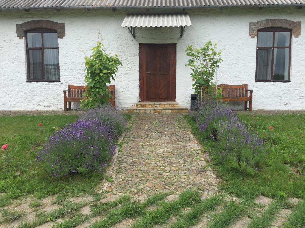 una casa con dos bancos y una puerta y flores púrpuras en Hotel Rafinad en Sharhorod