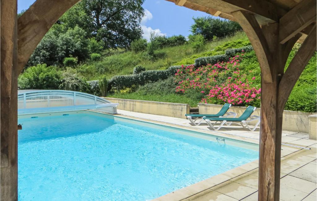 a swimming pool with two chairs and flowers at Awesome Home In Domfront En Champagne With Wifi, Outdoor Swimming Pool And Heated Swimming Pool in Domfront-en-Champagne