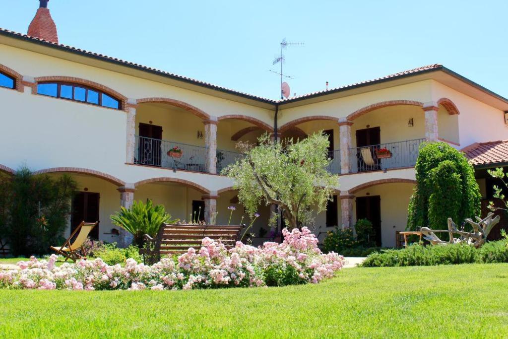 uma casa grande com um quintal com flores cor-de-rosa em Agriturismo Vecchio Imposto em Massa Marittima