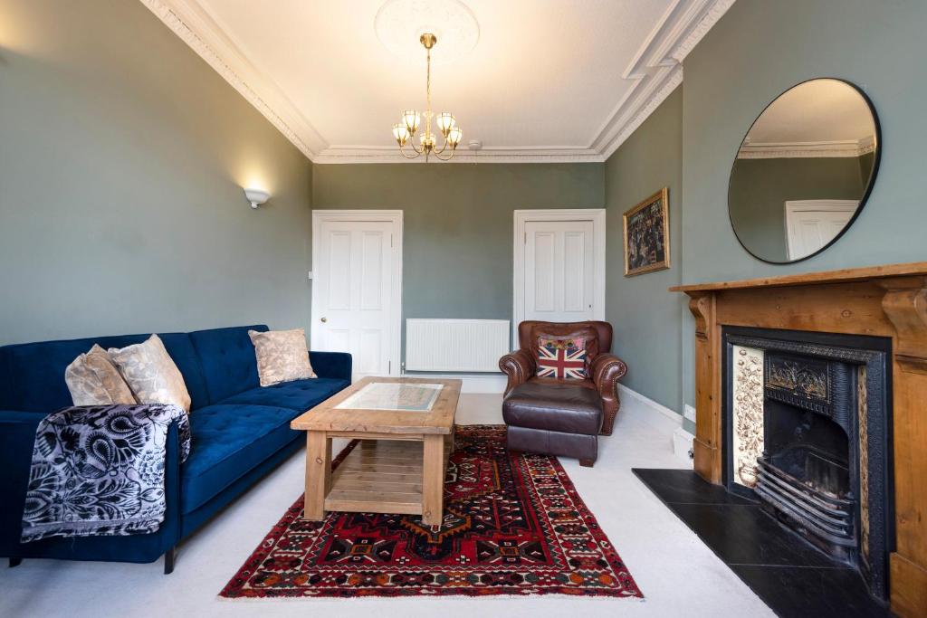 ALTIDO Old Town 1-Bed Apartment with Stunning Views في إدنبرة: غرفة معيشة مع أريكة زرقاء ومدفأة