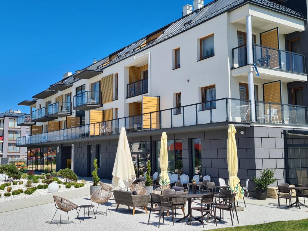 a hotel with a patio with chairs and umbrellas at COSTA Apartamenty w Sarbinowie in Sarbinowo