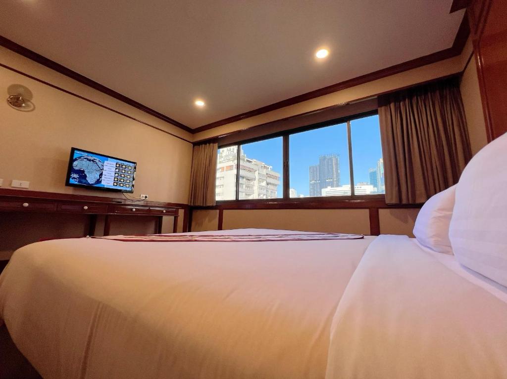 een slaapkamer met een groot wit bed en een raam bij The Promenade Hotel - SHA Plus in Bangkok