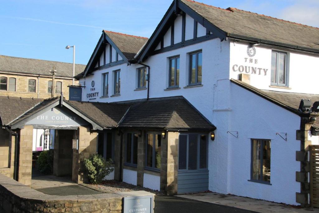 a white building with a sign on the side of it at County Lodge & Brasserie in Carnforth