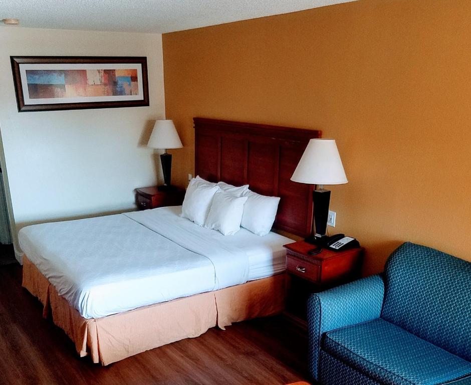 Habitación de hotel con cama y silla en Sylvania Inn-Sylvania,Statesboro, GA-Georgia Southern Univ GSU, en Sylvania