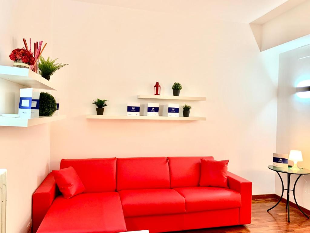 un sofá rojo en una sala de estar con estanterías en House Nervi 2 by Holiday World en Génova