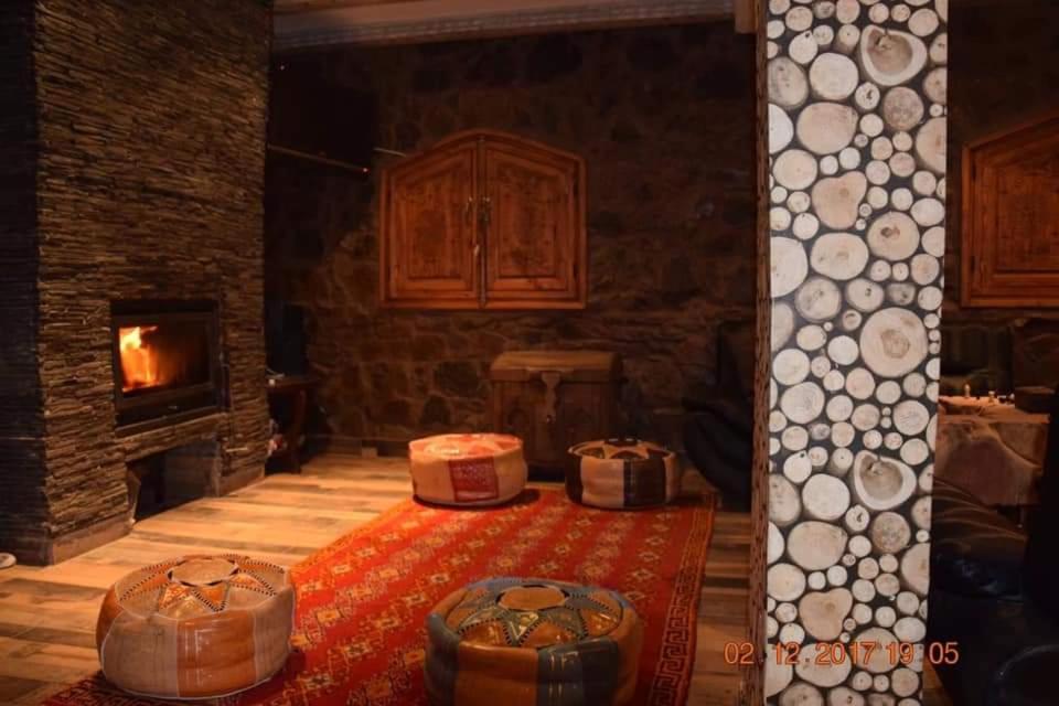 a living room with a fireplace and a table with a rug at Mountain Paradise Chalet in Imlil