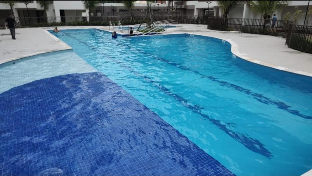 uma grande piscina com água azul em Apartamento na Praia Martim de Sá com linda vista em Caraguatatuba