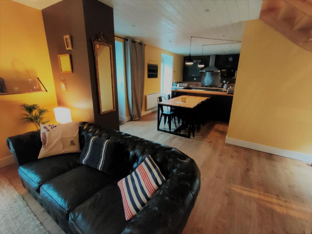 a living room with a black leather couch and a kitchen at Maison de pêcheur Port de plaisance Tréboul in Douarnenez