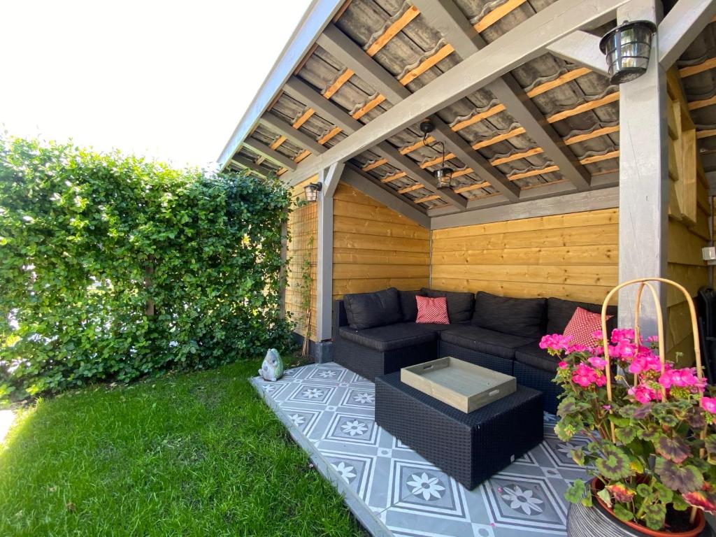 een patio in de achtertuin met een bank en een pergola bij Vakantiewoning Scheldestraat 23 Zoutelande, dicht bij Domburg in Zoutelande