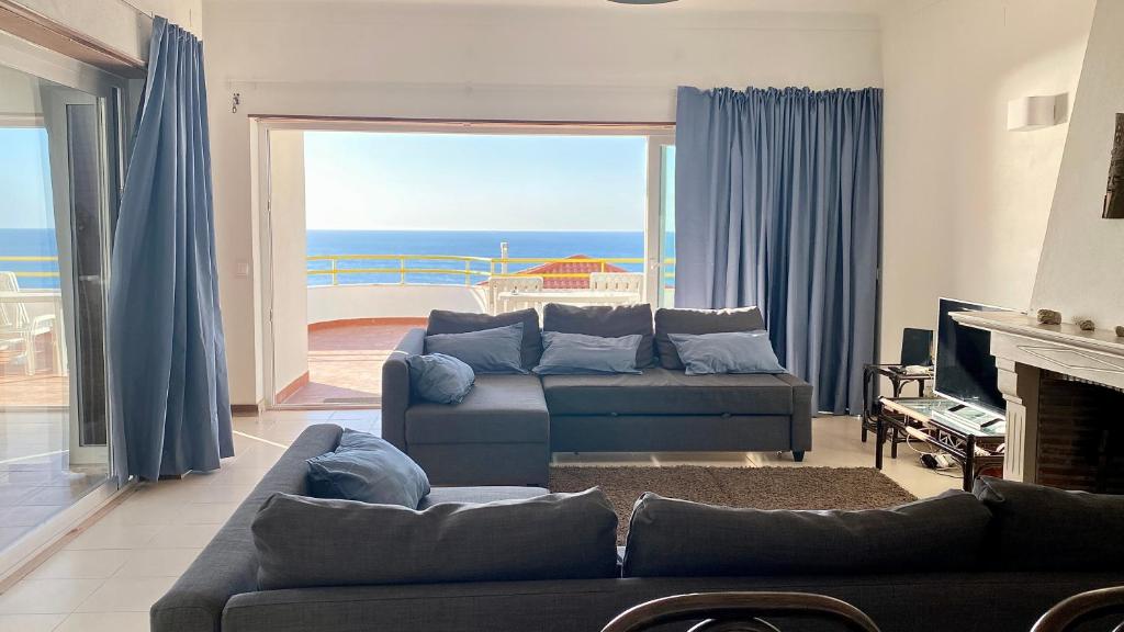 a living room with a couch and a view of the ocean at Ericeira Panoramic Sea View Apartments in Ericeira
