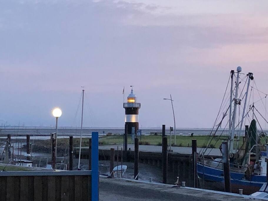 a lighthouse in the middle of a harbor with boats at Wohnung "Strandturm" in Wremen am Deich in Wremen