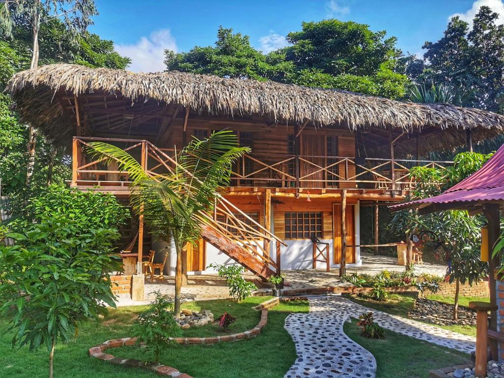 a house with a thatched roof and a garden at La Finca Lorena Tayrona in El Zaino