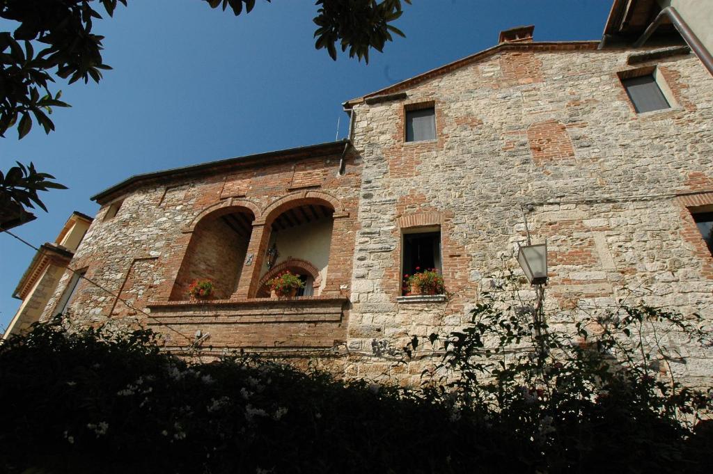 un edificio de ladrillo con dos ventanas y flores en él en Palazzo Bizzarri, en Rapolano Terme