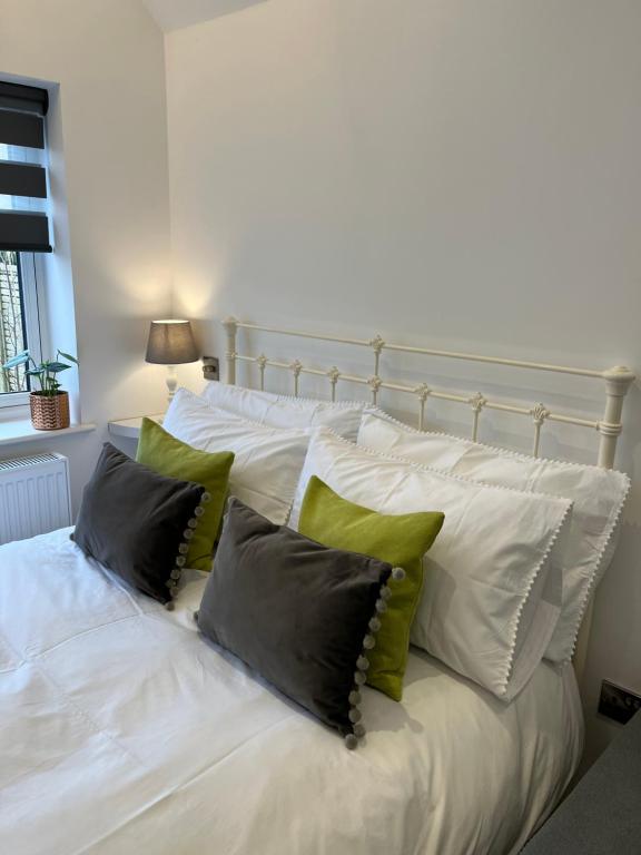 Una cama blanca con cuatro almohadas. en The Snug- With Private parking en Whitstable
