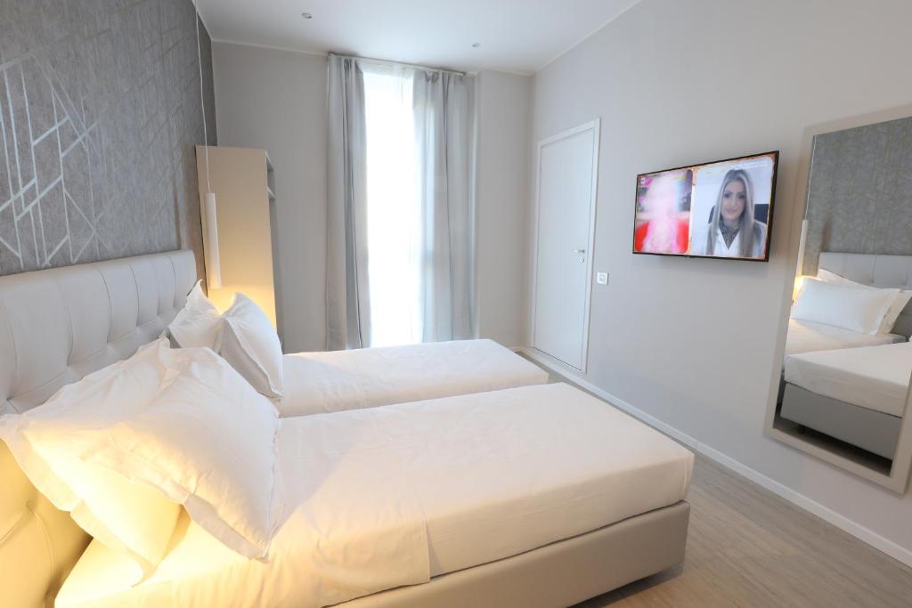 ein weißes Schlafzimmer mit einem Bett und einem Spiegel in der Unterkunft Cadorna Luxury Hotel in Mailand