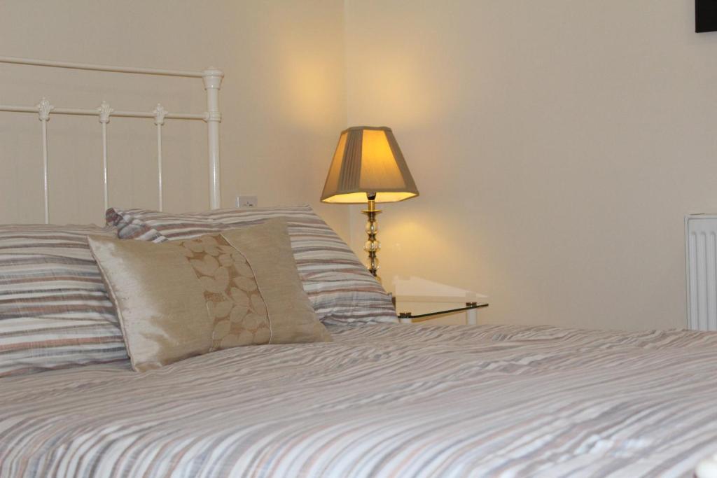 um quarto com uma cama com um candeeiro ao lado em The Bulls Head em Chichester