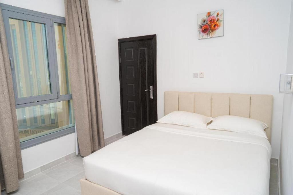 um quarto com uma cama branca e uma janela em Atlantis Suites Hotel em Kuwait