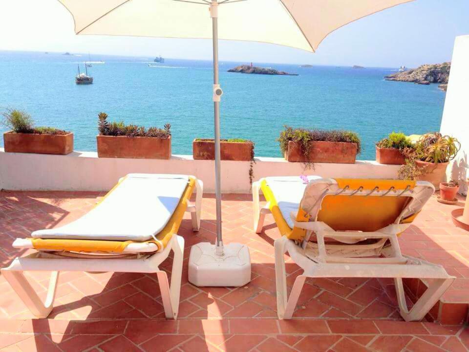 zwei Stühle und ein Sonnenschirm auf einer Terrasse mit Meerblick in der Unterkunft Mirador de la Virgen Ático con terraza y estudio sin terraza in Ibiza-Stadt