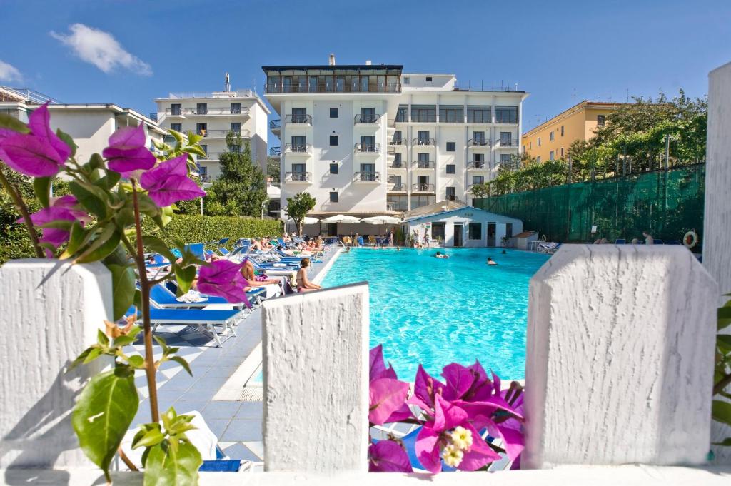 una piscina con sillas y flores frente a un edificio en Grand Hotel Flora, en Sorrento