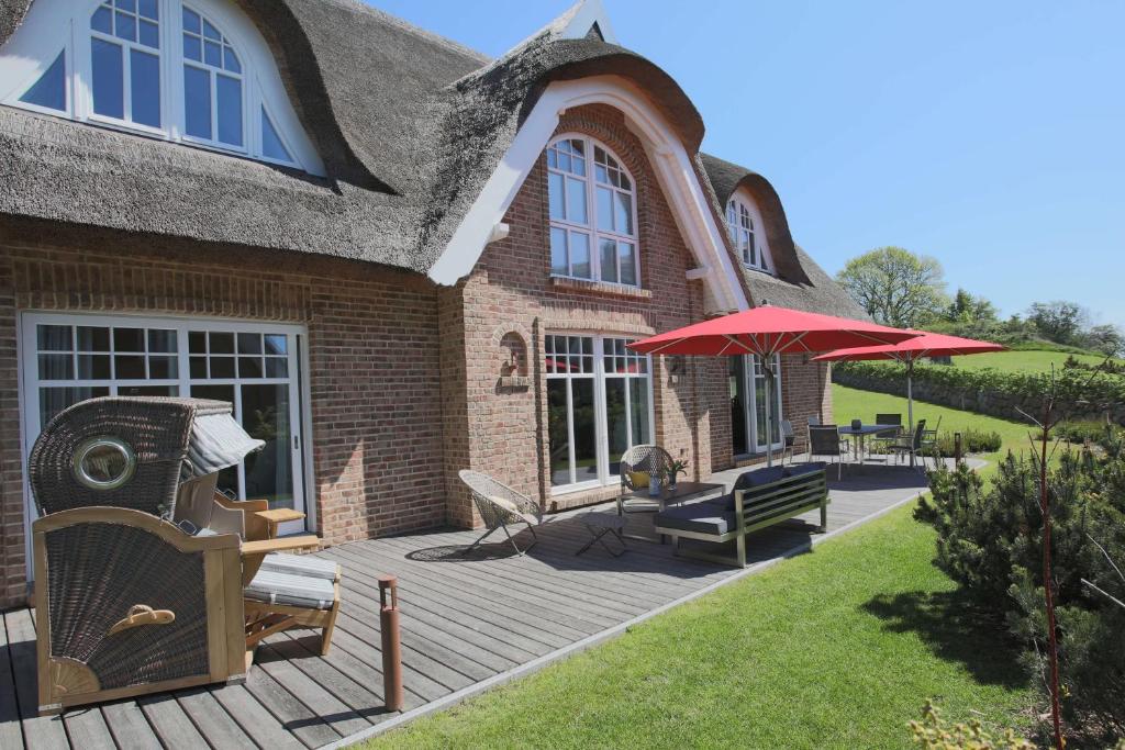 a house with a wooden deck with a red umbrella at Strandhaus Buskam im Mönchgut auf Rügen in Lobbe