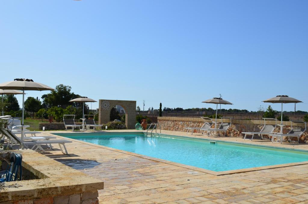a large swimming pool with chairs and umbrellas at Agriturismo Residenza Gemma in Porto Cesareo