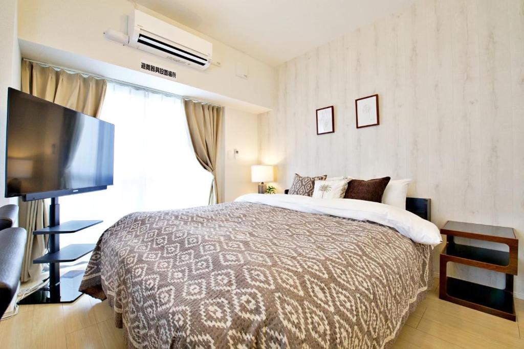 a bedroom with a bed and a flat screen tv at Daruma Mansion - Vacation STAY 16088v in Naha