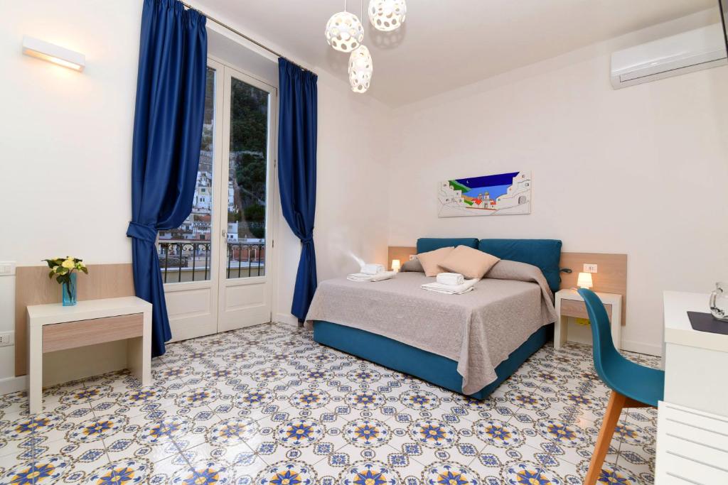 a bedroom with a bed and blue curtains and a window at Antica Residenza Amalfitana in Amalfi