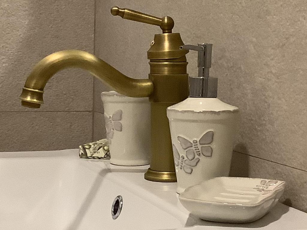 zlew w łazience ze złotym kranem i toaletą w obiekcie Ezüst Boróka Apartman w Egerze