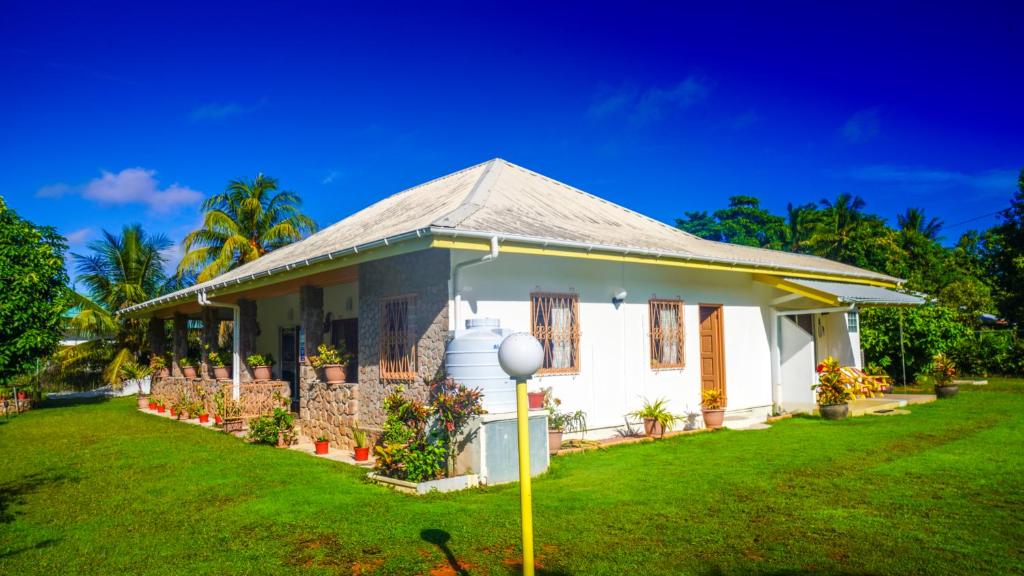 uma pequena casa branca com um jardim de relva em Villa Antonia em La Digue