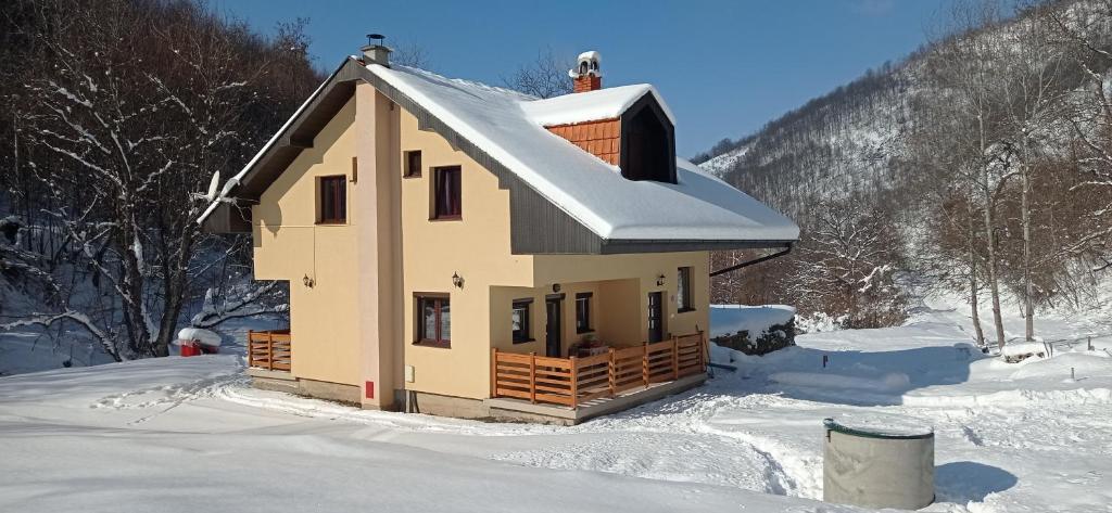 a house with snow on the roof in the snow at Vila Nada in Crni Vrh