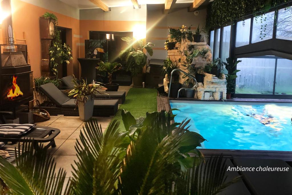 a large indoor swimming pool in a room with plants at Desirad in La Clisse