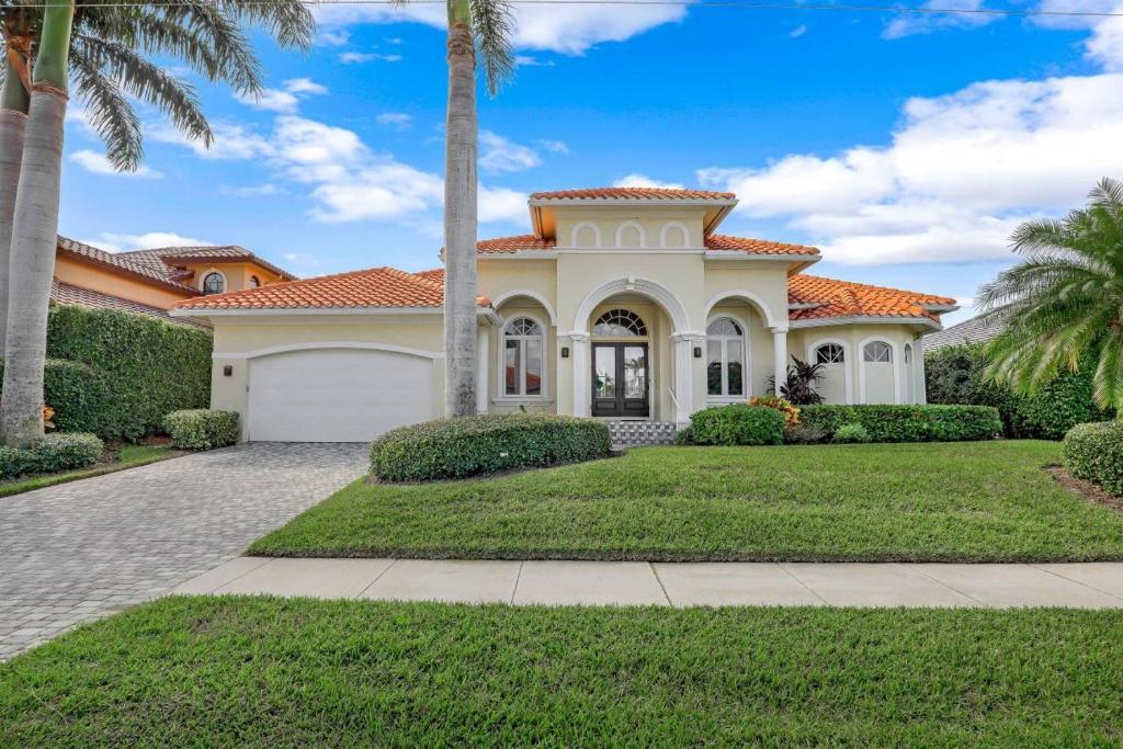 une maison avec un palmier devant dans l'établissement SW exposure home on wide canal with pool and spa, à Marco Island