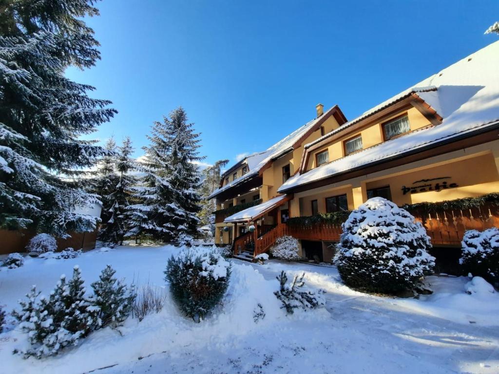a building with snow on the ground next to trees at Apartmány PACIFIC in Demanovska Dolina