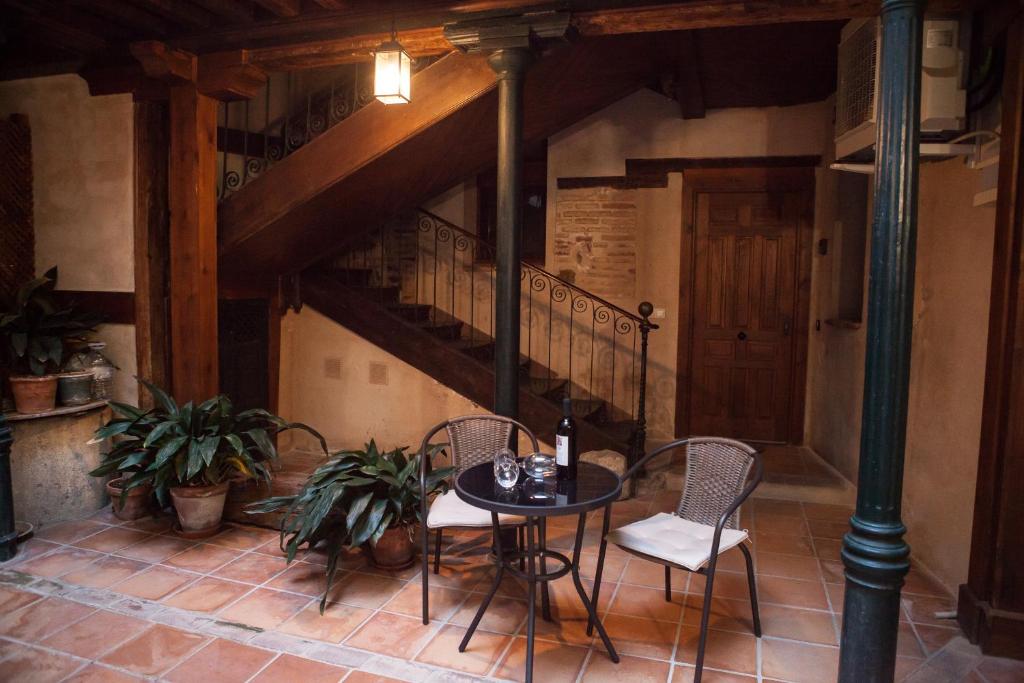 una mesa y sillas en una habitación con escalera en SEÑORÍO de ORGAZ "Con Patio TOLEDANO" en Toledo