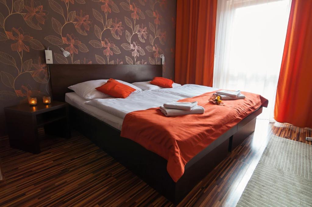 a bedroom with a bed with red curtains and a window at Penzion Beryl in Košice