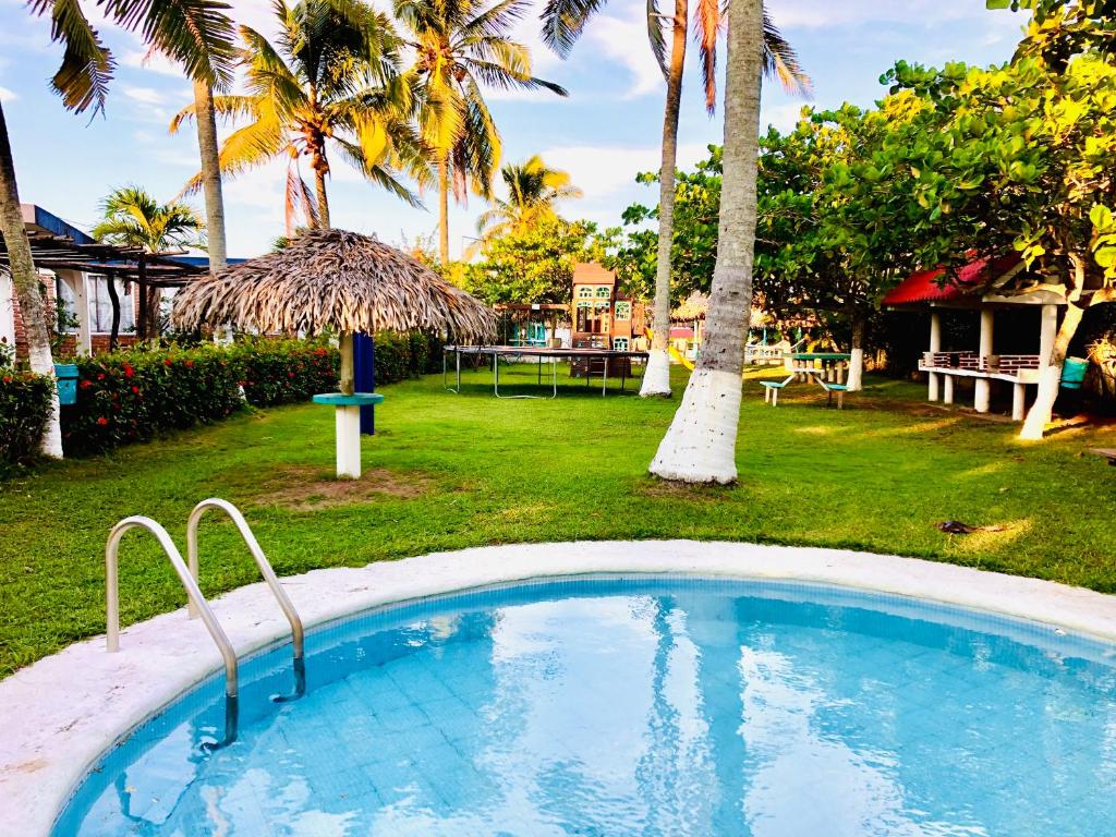 a swimming pool in a yard with palm trees at Hotel Bungalows Marbella Costa Esmeralda in Monte Gordo