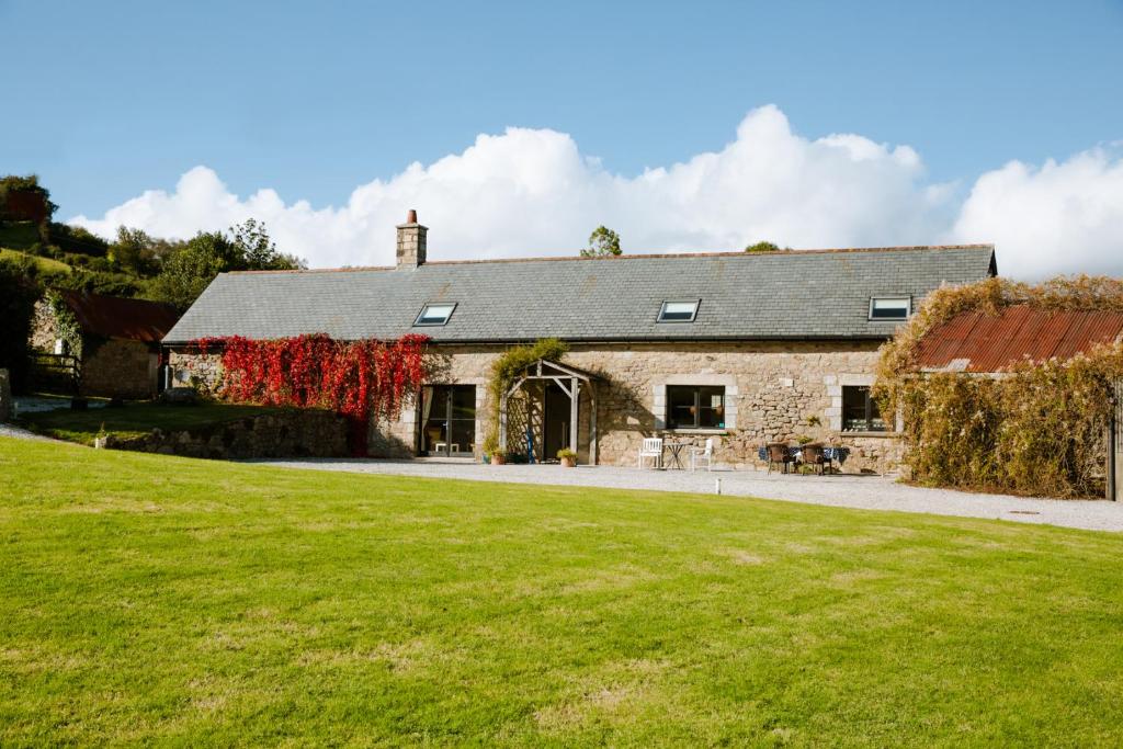 an old stone house with a green lawn at Higher Weddicott Barn Holiday Cottage - Self Catering in Chagford