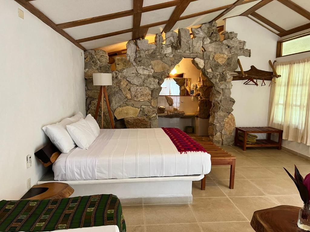 a bedroom with a bed and a stone wall at Finca Vallescondido in El Caobano
