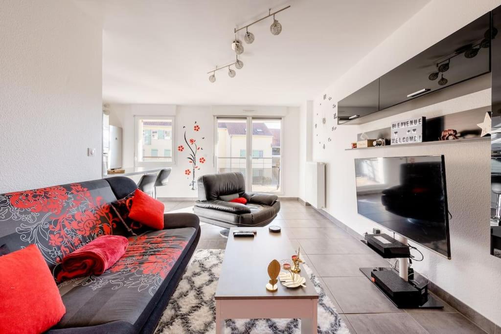 sala de estar con sofá negro y almohadas rojas en Spacieux - 4 pers' - Balcon - 2 lits - Parking, en Woippy