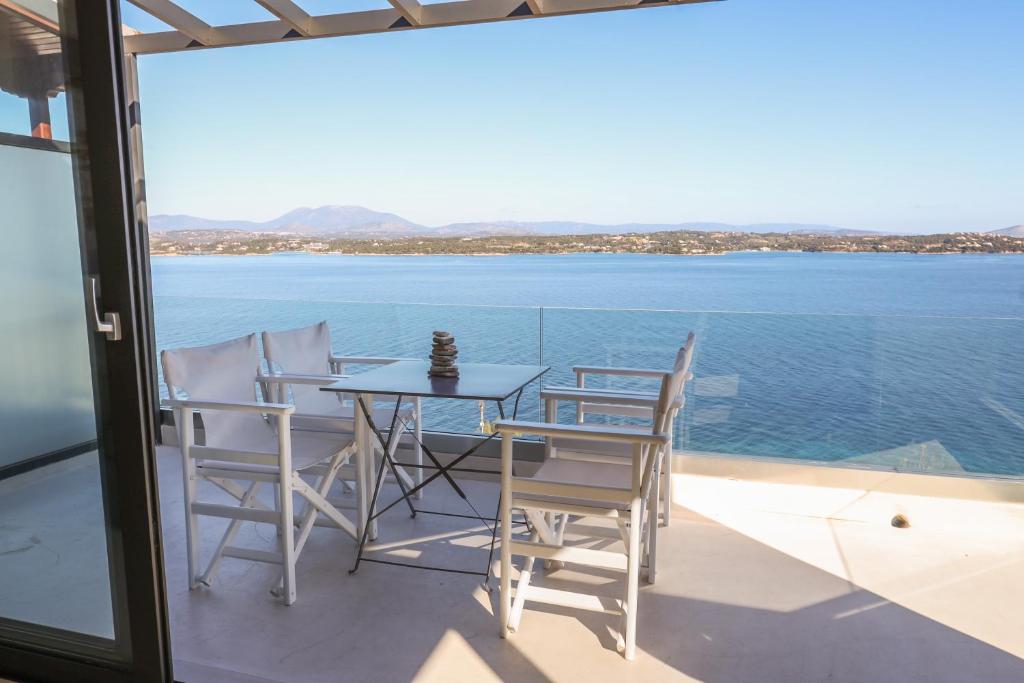 a table and chairs on a balcony with a view of the water at Raise Spetses Sea View Villa in Spetses