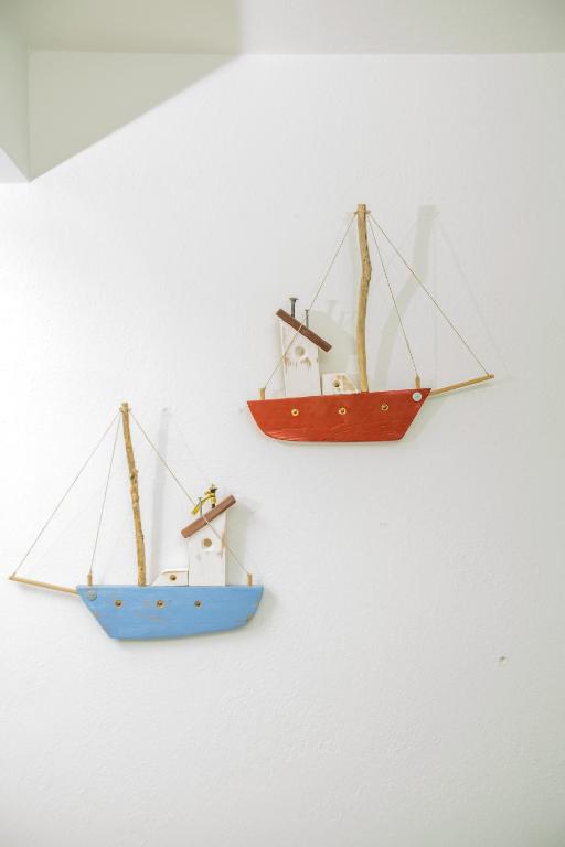 three small wooden boats hanging on a wall at Raise Spetses Sea View Villa in Spetses